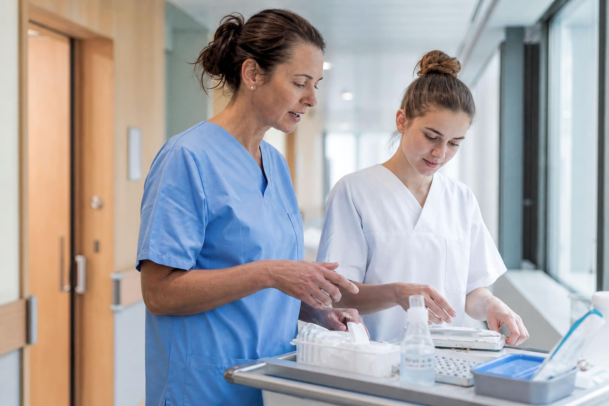 Eine Berufsbildnerin erklärt einer Lernenden im Spital den nächsten Handgriff.